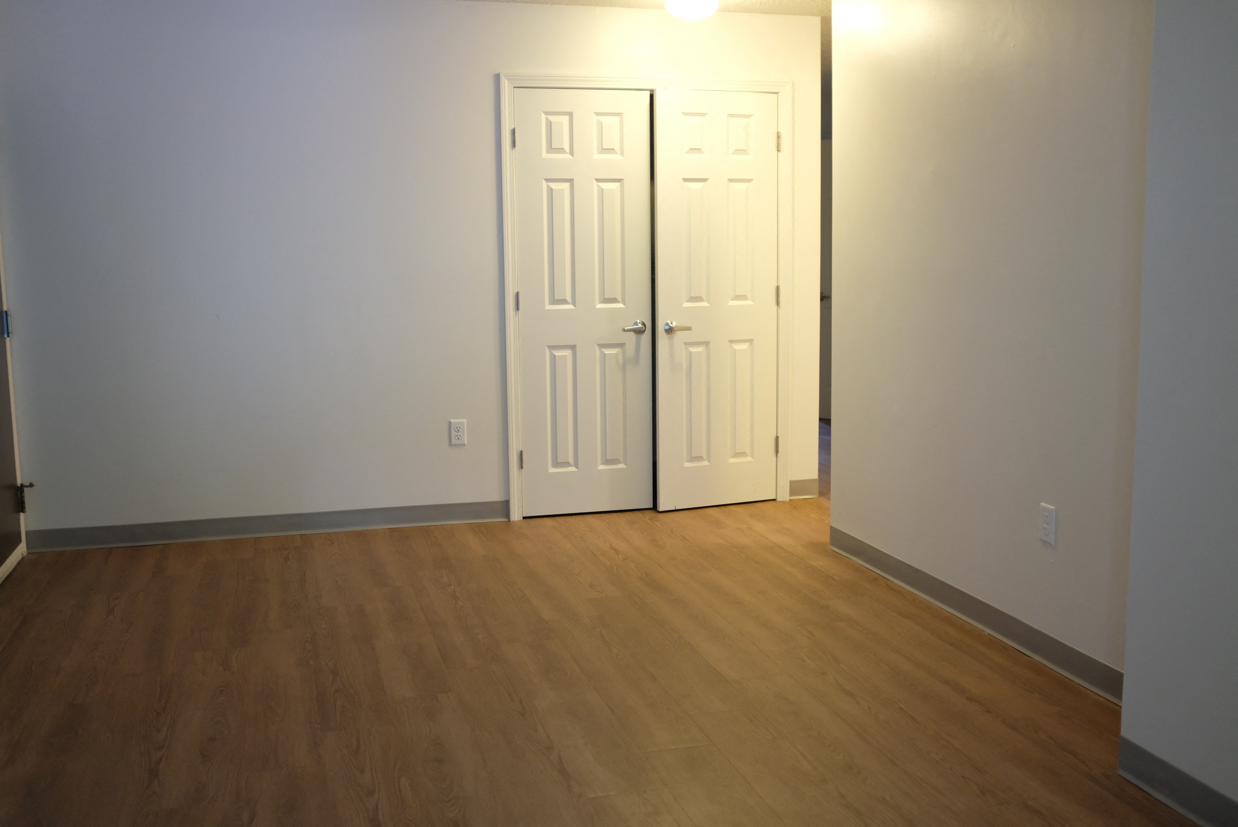an empty living room with two doors and a wood floor